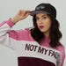 Woman wearing Cappellino driptrap black cap with innovative design for hair protection during showers, styled with a pink and white sweatshirt.