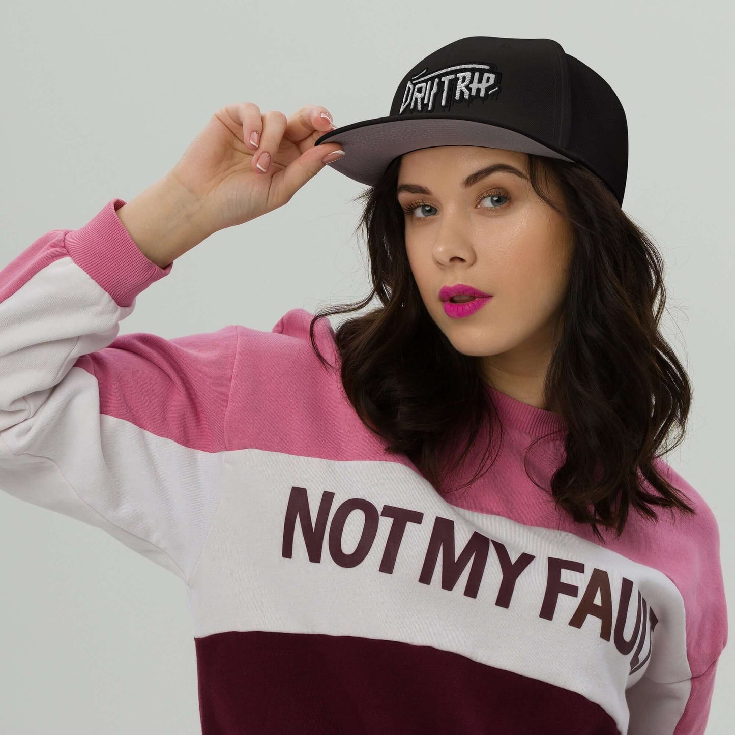 Woman wearing Cappellino driptrap black cap with innovative design for hair protection during showers, styled with a pink and white sweatshirt.