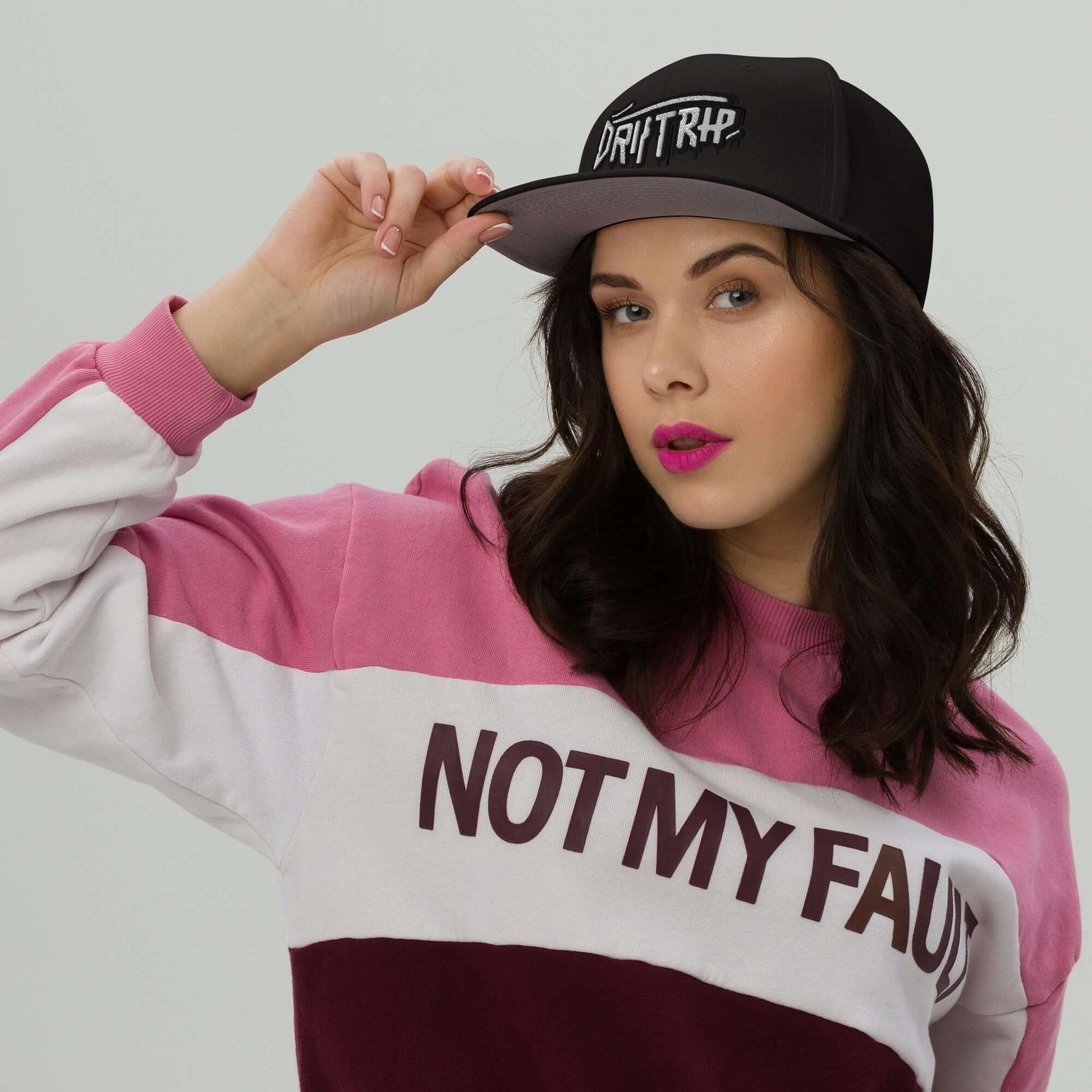 Woman wearing Cappellino driptrap black cap with innovative design for hair protection during showers, styled with a pink and white sweatshirt.