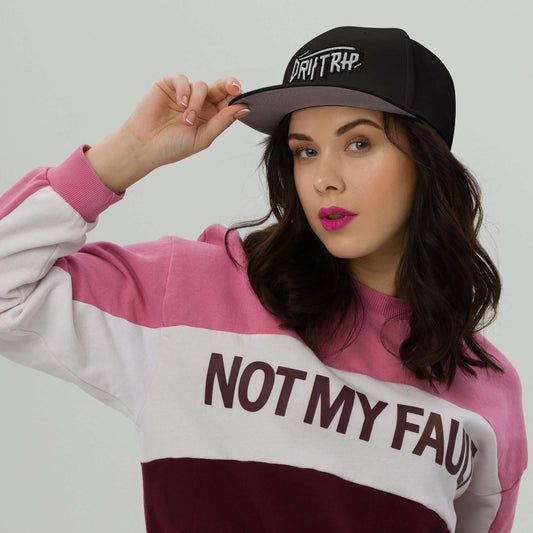 Woman wearing Cappellino driptrap black cap with innovative design for hair protection during showers, styled with a pink and white sweatshirt.